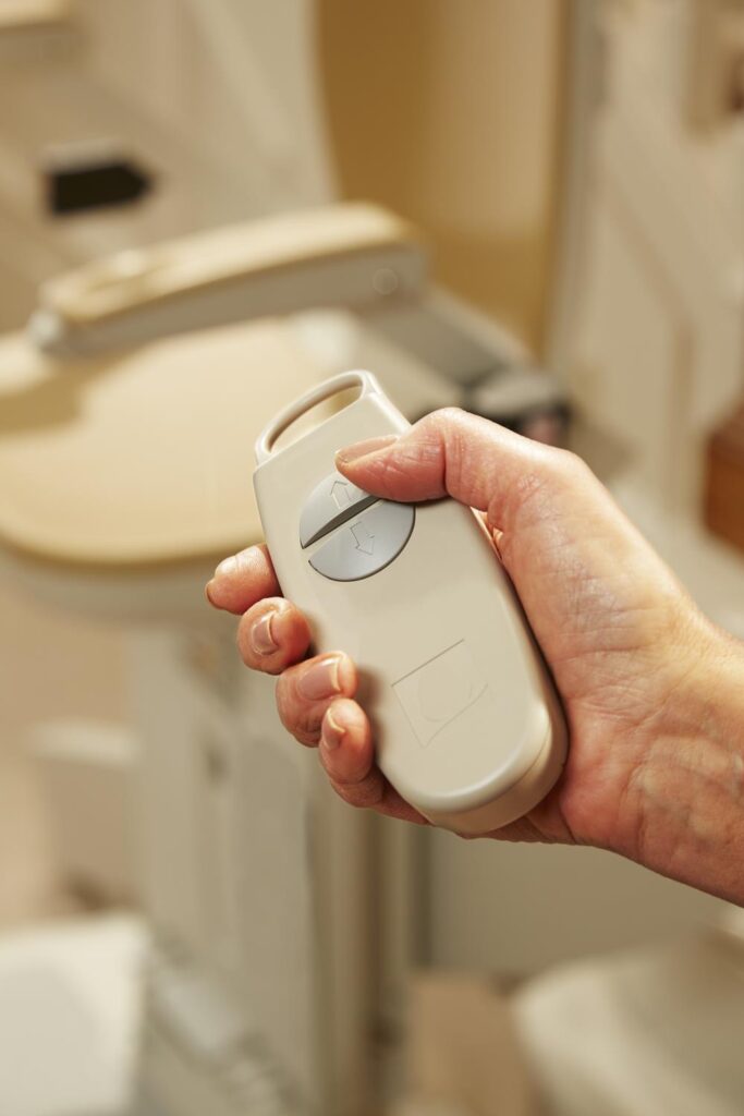 A hand holding a stairlift remote control