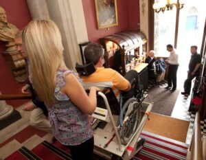 Operator using a Stairmate Major stairclimber to transport a passenger down a flight of stairs at the Garrick Club, London