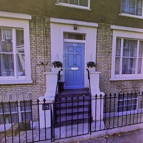 House with steps leading up to the front door and black railings.