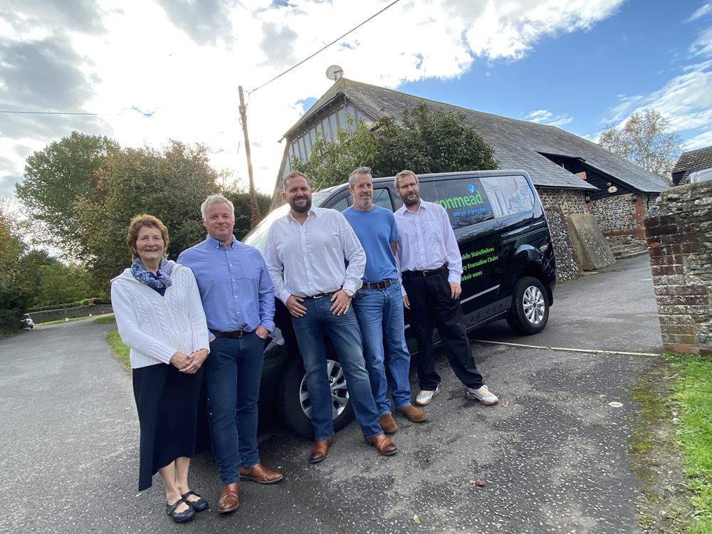 The Baronmead International company team standing in front of a black van at their headquarters in Flansham, West Sussex.