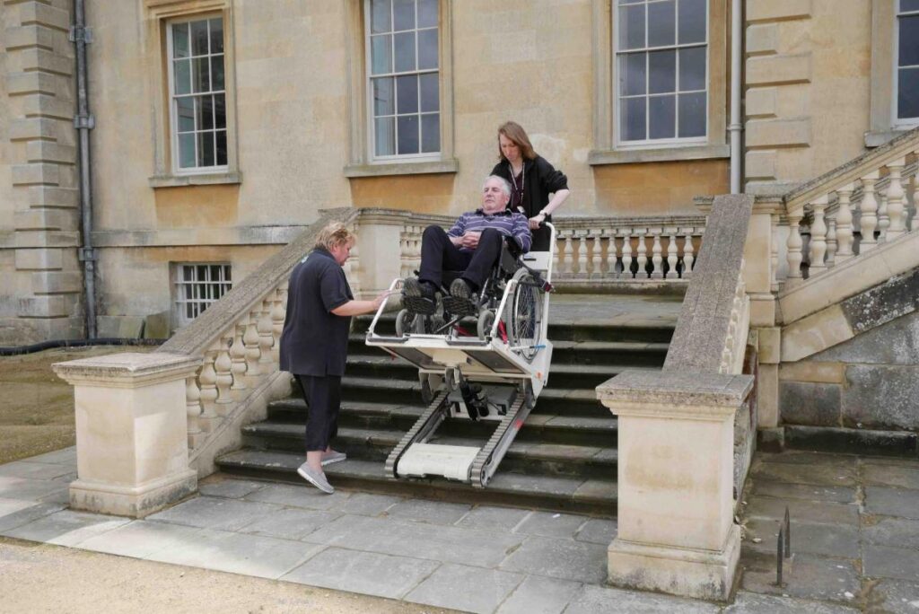 A stair climber operator using a Stairmate Major to allow an elderly man to access some stone steps at an historic building